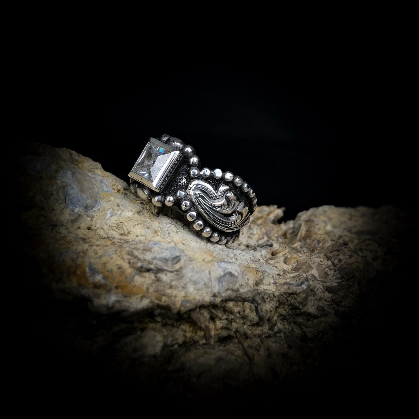 Rockin Out Jewelry’s “Fancy” is a handcrafted solid sterling silver ring that has a classy and elegant look similar to our “Texas Angel” ring. The “Fancy” features a low profile setting with a 6mm cubic zirconia or Kingman stone in the center and a western style beaded border and overlay scrolls on both sides of the ring.