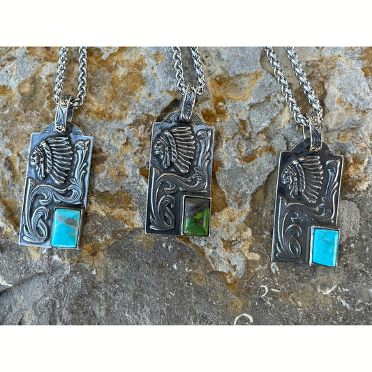 The Indian Dog Tag is a custom sterling silver stunningly detailed pendant that features a 10mm x 14mm bezel set genuine Kingman Turquoise stone from the Kingman Mines in Kingman, AZ and an overlaid exquisite hand engraved Indian head along with an overlaid western style hand engraved scrolling. This pendant is a true work of art and real statement maker. The pendant is the size of a standard dog tag and measures at 1 5/8" long by 1" wide.