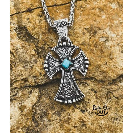 The "Crossfire" Pendant is a large custom sterling silver cross with a unique border adorned with an inlaid western style hand engraving that features a 6mm genuine Kingman Turquoise stone. The cross measures 2" x 1 3/8" wide. Natural Kingman Turquoise Stones vary in color from stone to stone.