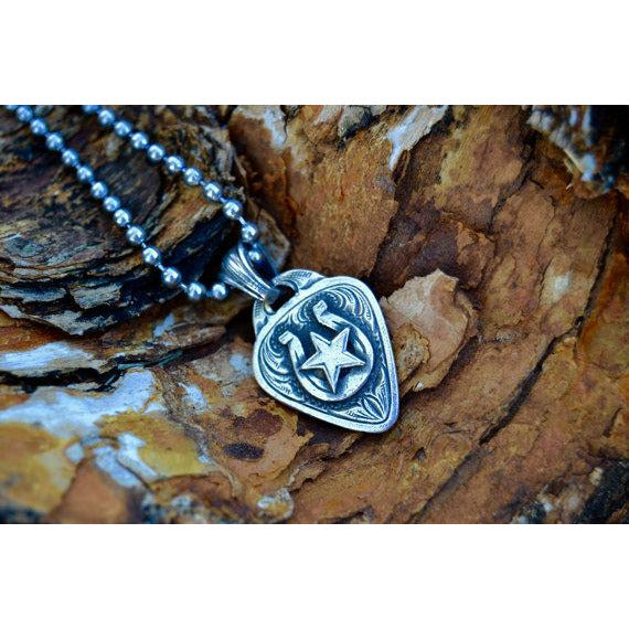 The "Lucky Rockstar" Guitar Pick Pendant is a handmade solid sterling silver pendant with a western style engraved scrolling in the background of an overlaid horseshoe with a star in the center of the horseshoe.