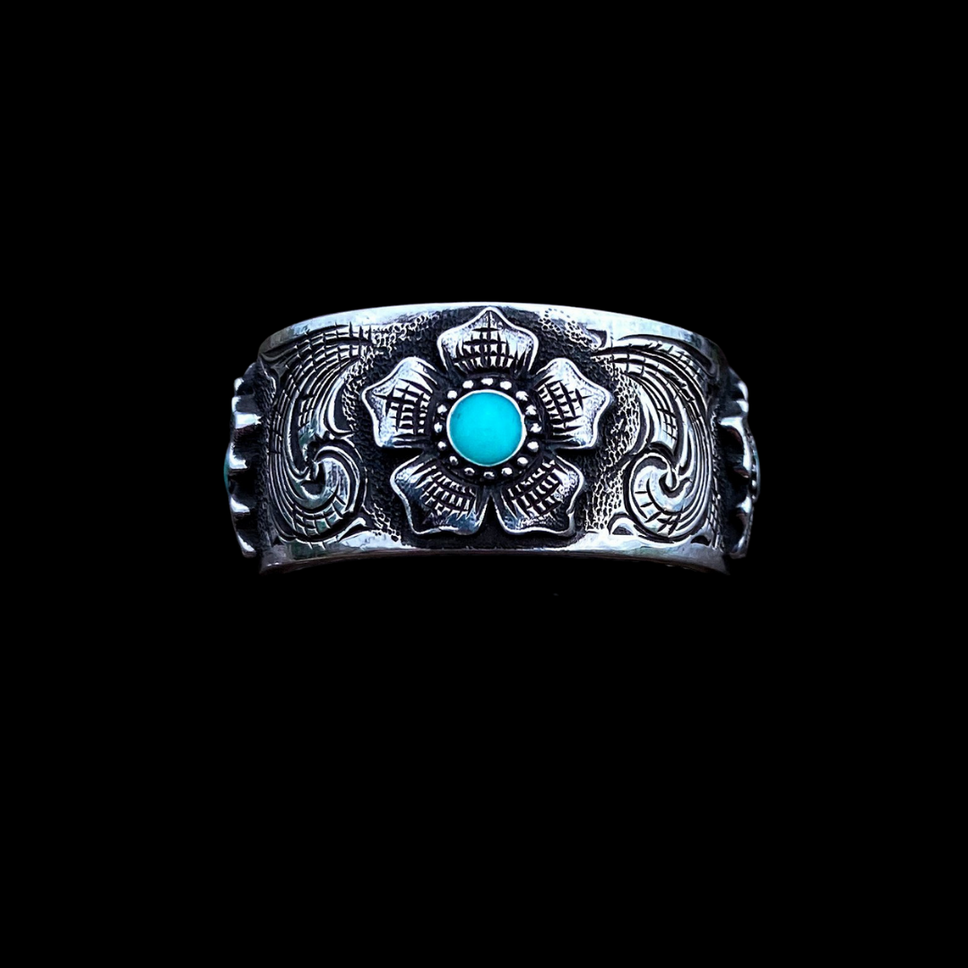 “Magnolia” is a custom women’s solid sterling silver band that features western style hand engraving accented with 3 beautiful, engraved magnolias that are filled in the center with turquoise inlay. This hefty band is about 10.5mm wide and heavy duty enough for everyday wear!