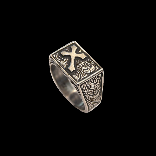 "Survivor" is a handmade solid sterling ring that features an overlaid cross and western style hand engraved scrolling on the top of the ring as well as on either side of it tapered band.