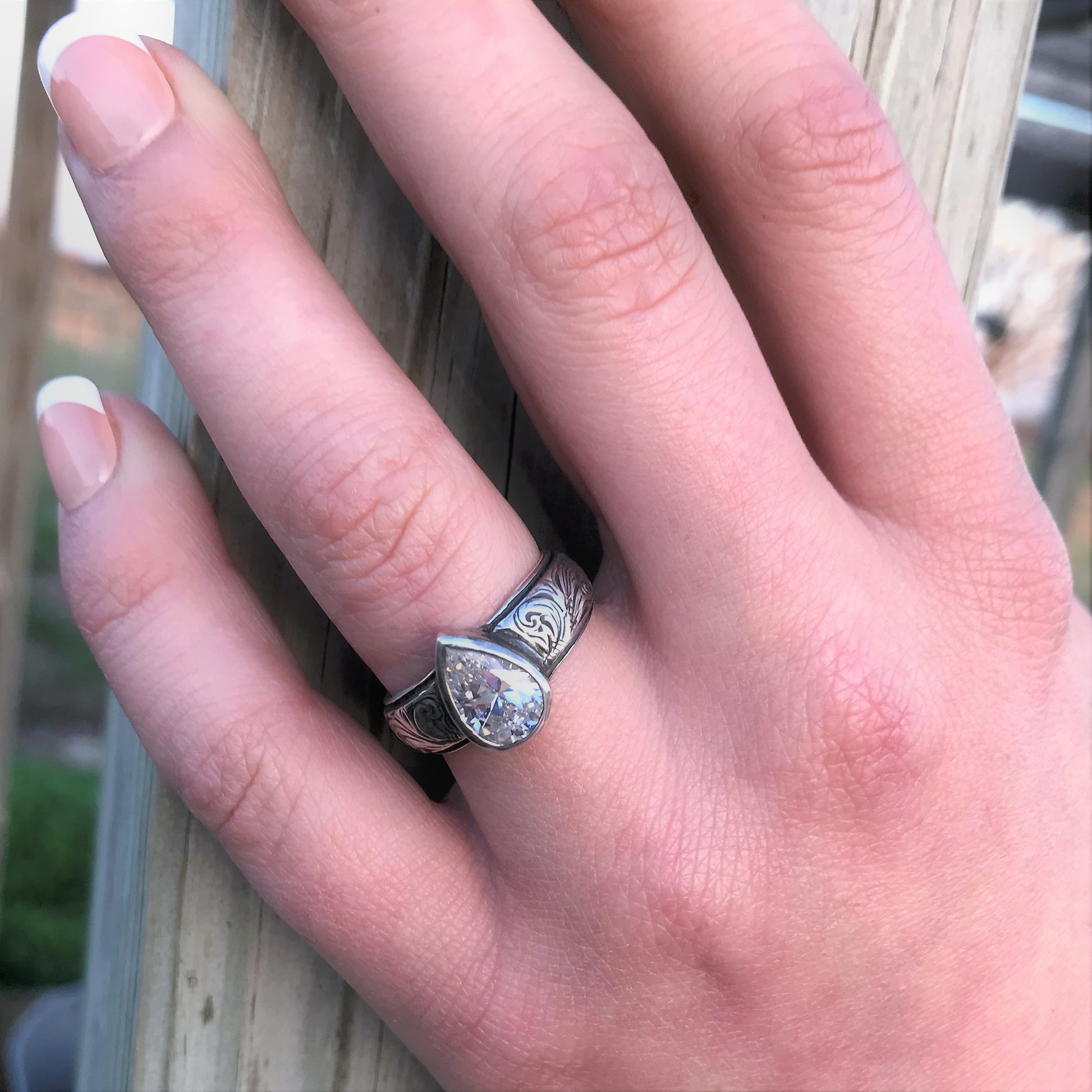 Sterling Silver ring with a pear cut CZ stone. This ring has a beautiful hand engraved western style scrolling throughout the band. 