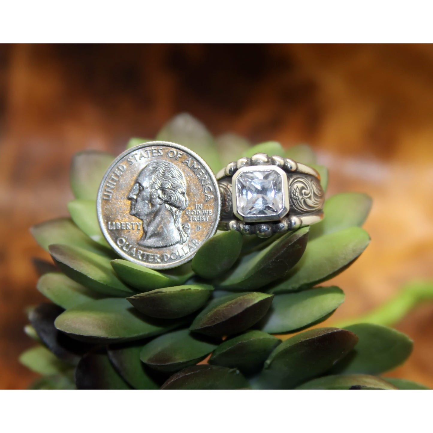 "Jessie" is a handmade solid sterling silver ring with an 8 mm cut corner cubic zirconia bezel set in a low-profile setting. This ring features western hand engraved scrolling on each side of the ring.