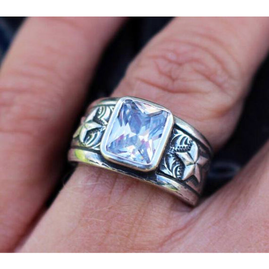 "Kate" is a sterling handmade silver ring with a 9mm x 7mm emerald cut bezel set cubic zirconia. This ring features a 3D star overlaying western hand engraved scrolling on each side of the ring.