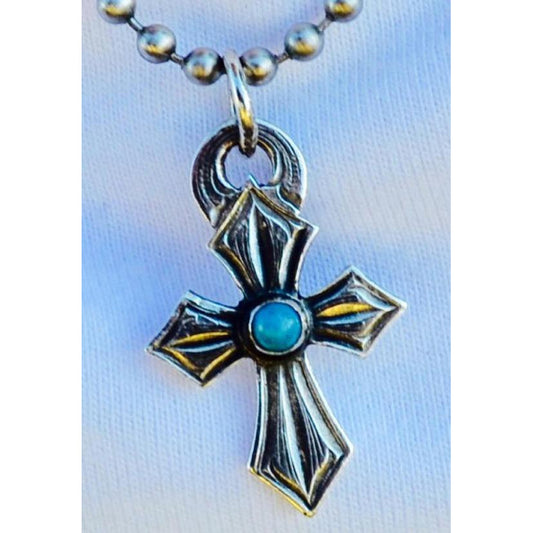 The "Lil Sprit" Turquoise Cross pendant is a handmade small sterling silver cross that features a round bezel set Genuine Kingman Turquoise Stone from the Kingman Mines in Kingman, AZ. This cross measures at 3/4" X 1 1/4".
