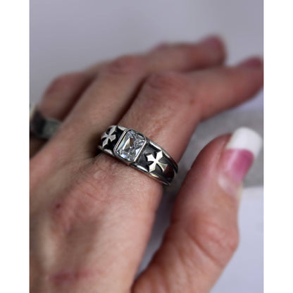 The Creed Ring is handmade sterling silver ring that is elegantly simple, but its beauty speaks volumes. Its smooth tapered band features a cross overlay on either side of its 8 mm x 6 mm emerald cut cubic zirconia stone. 