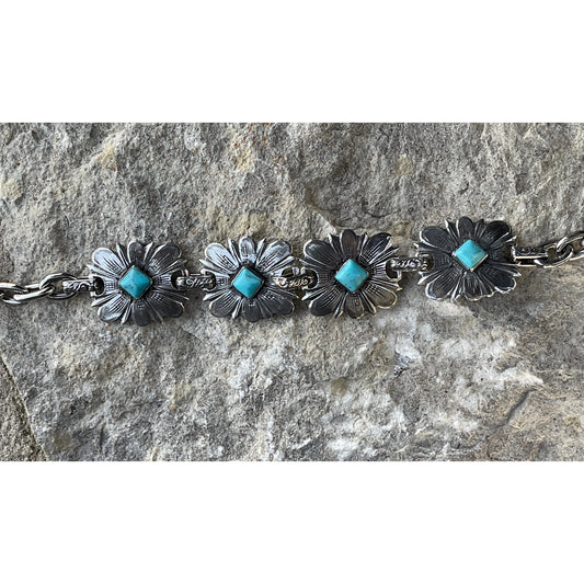 The "Daisy Turquoise" handmade sterling silver link bracelet features 4 hand engraved flowers with 6mm round genuine Kingman Turquoise from the Kingman Mines in Kingman, AZ set in the center of each flower and is connected with small hand engraved links and has our Rockin Out logo on the inter-locking clasp. 