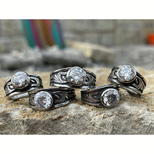 "Cheyenne" is a handcrafted sterling silver ring with a tapered band with overlaid western style scroll work on each side of the ring and features a 6mm cz stone.