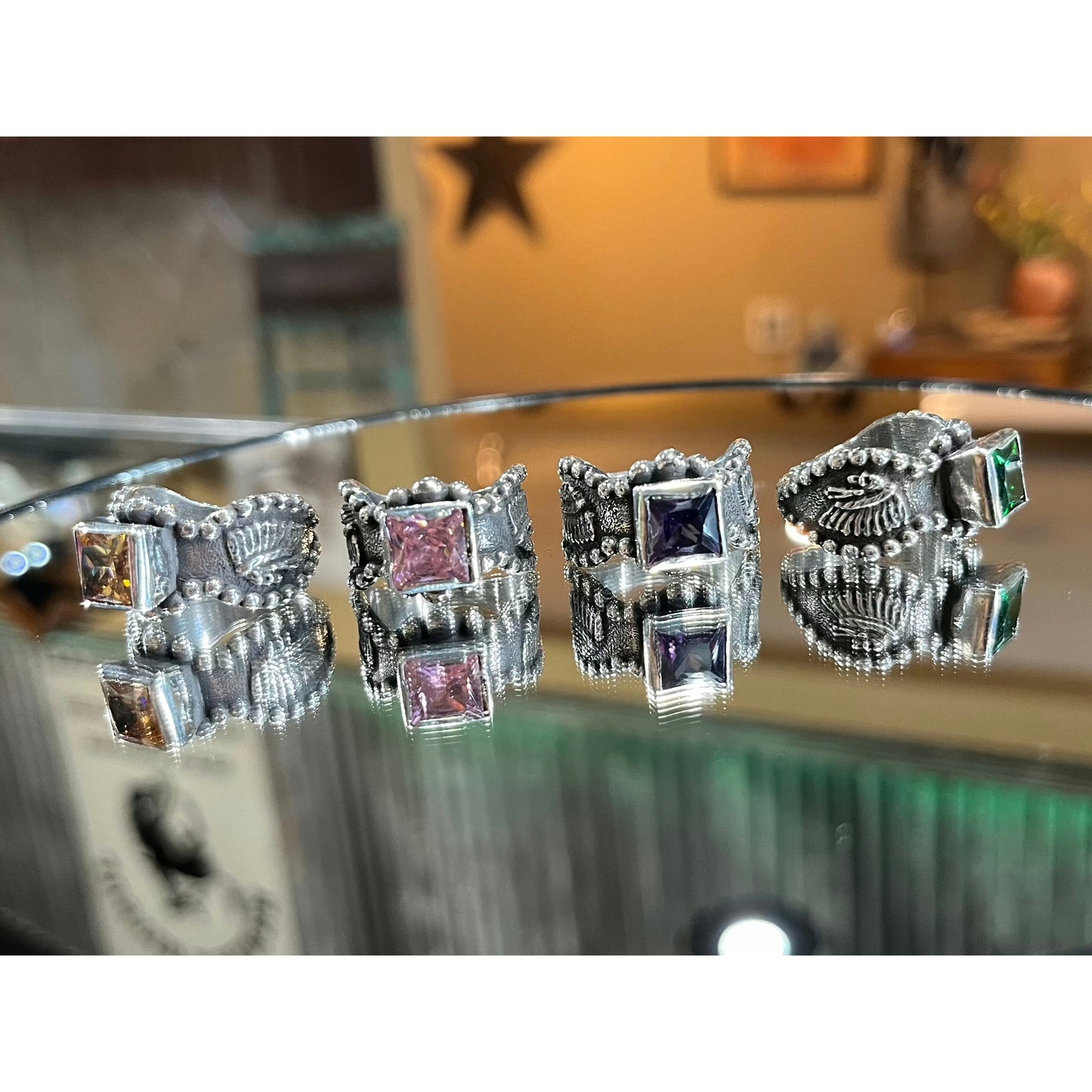 "Dakota" is a handmade sterling silver ring that has a unique border all the way around the ring with an 8mm bezel set princess cut cubic zirconia that features an overlaid 3D Indian Chief head on each side of the ring.