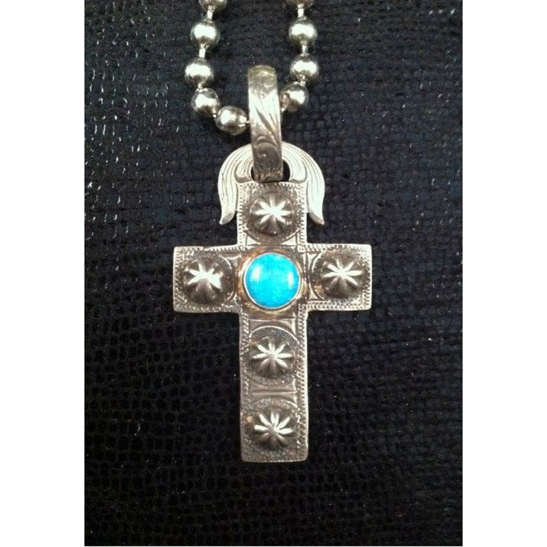 The "Maisie Turquoise Cross Pendant " is a handmade sterling silver pendant and has a very unique western style engraved scrolling, the center of the cross features a round bezel set Kingman Turquoise stone from the Kingman Mines in Kingman, AZ. They measure at 1 1/8" x 1 3/4".
