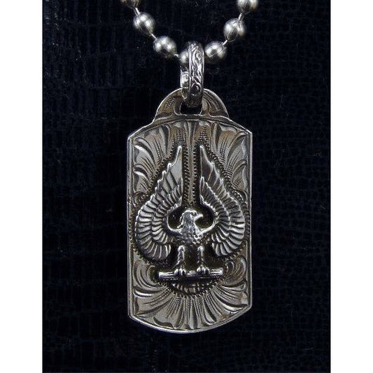 The "Eagle" Dog Tag is handmade a solid sterling silver pendant that features true American History with an overlaid Eagle that will never go out of style and is complimented by the detailed western style hand engraving that gives this timeless piece the perfect finishing touch. This pendant is the size of a standard dog tag and measures at 1" x 2".