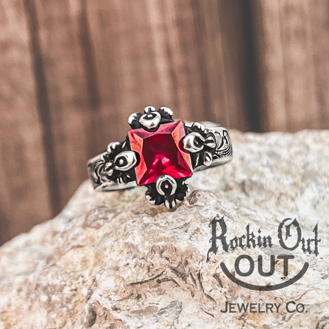 Eleanor ring is the picture of timeless class. This custom ring displays a beautiful princess cut Ruby stone and is hugged by four elegant, oversized prongs. Eleanor has an antiqued finish and a western style engraving to amplifying the stone. 