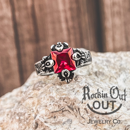 Eleanor ring is the picture of timeless class. This custom ring displays a beautiful princess cut Ruby stone and is hugged by four elegant, oversized prongs. Eleanor has an antiqued finish and a western style engraving to amplifying the stone. 
