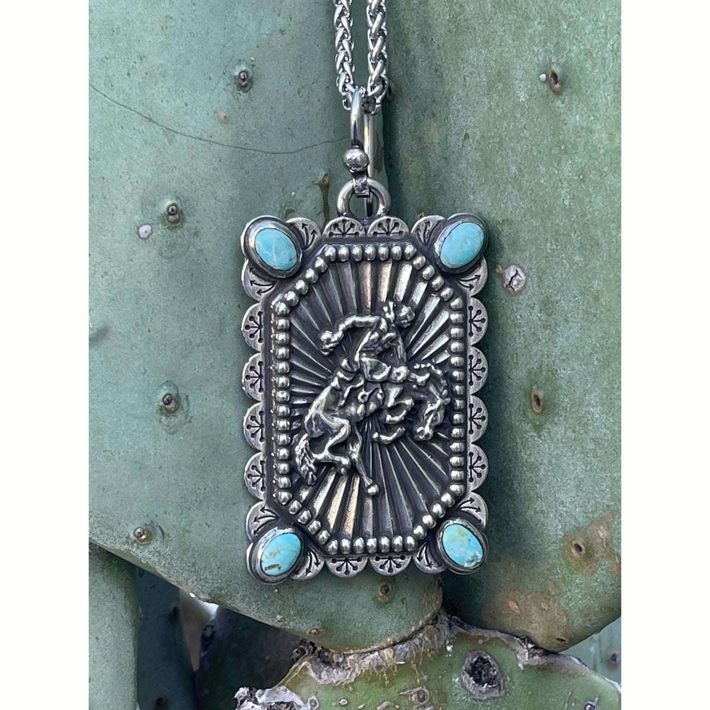 Sterling silver custom bucking horse pendant with 4 Kingman Turquoise Stones. This pendant measures 3. 5 x 2 inch and comes on a large beaded silver ball chain. 