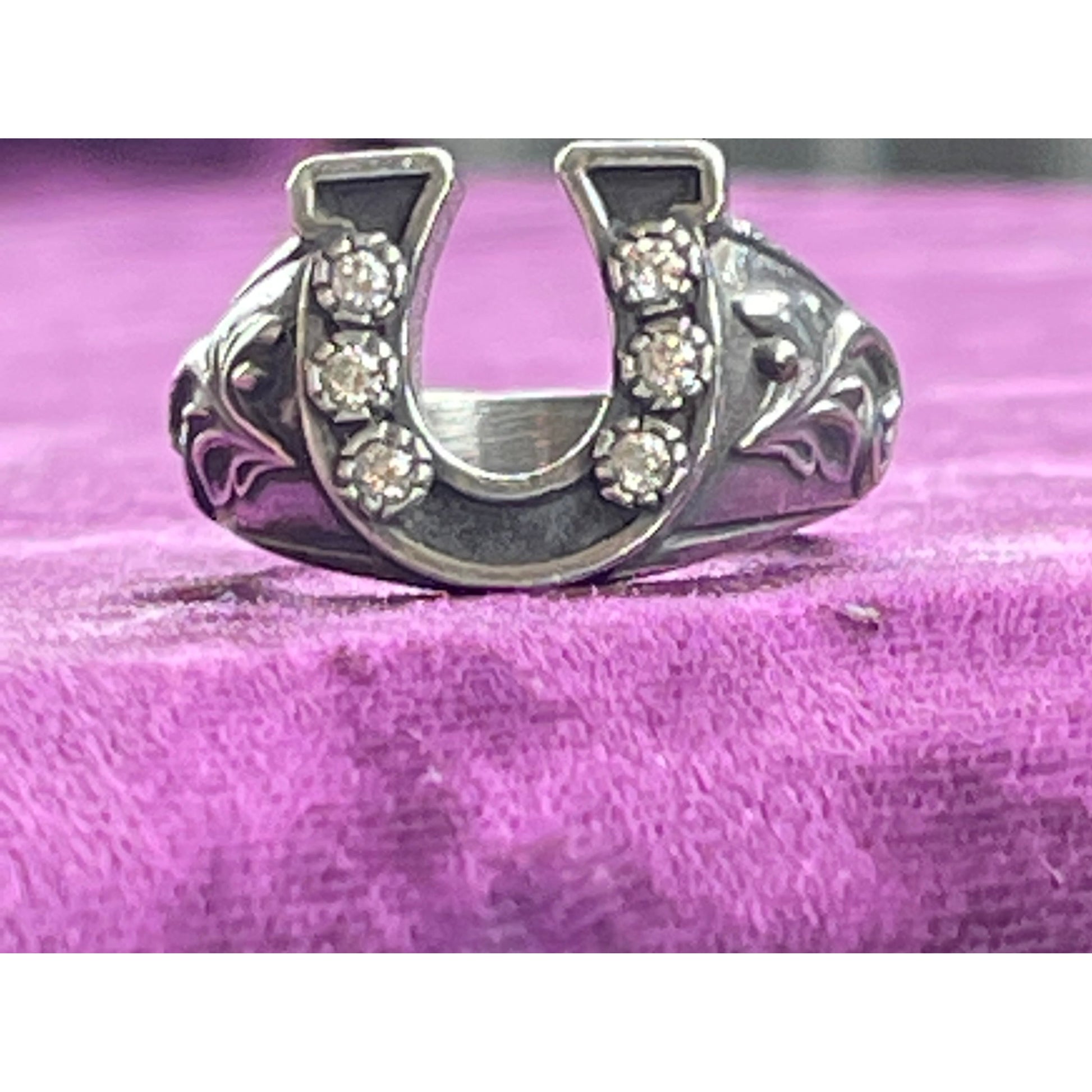 Custom sterling silver horseshoe ring set with cubic Zirconia stones along the horseshoe complimented by a beautiful scrolling on either side of the band. The band is slightly tapered for a very comfortable fit. 