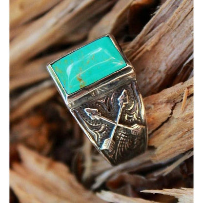 "Crossed Arrow" is a handmade sterling silver ring with a 10 mm x 14 mm bezel set with genuine Kingman Turquoise. This unique ring features 2 crossed arrows overlaid a western engraved scrolled on each side of the ring. Due to the uniqueness of turquoise the color will vary from ring to ring.