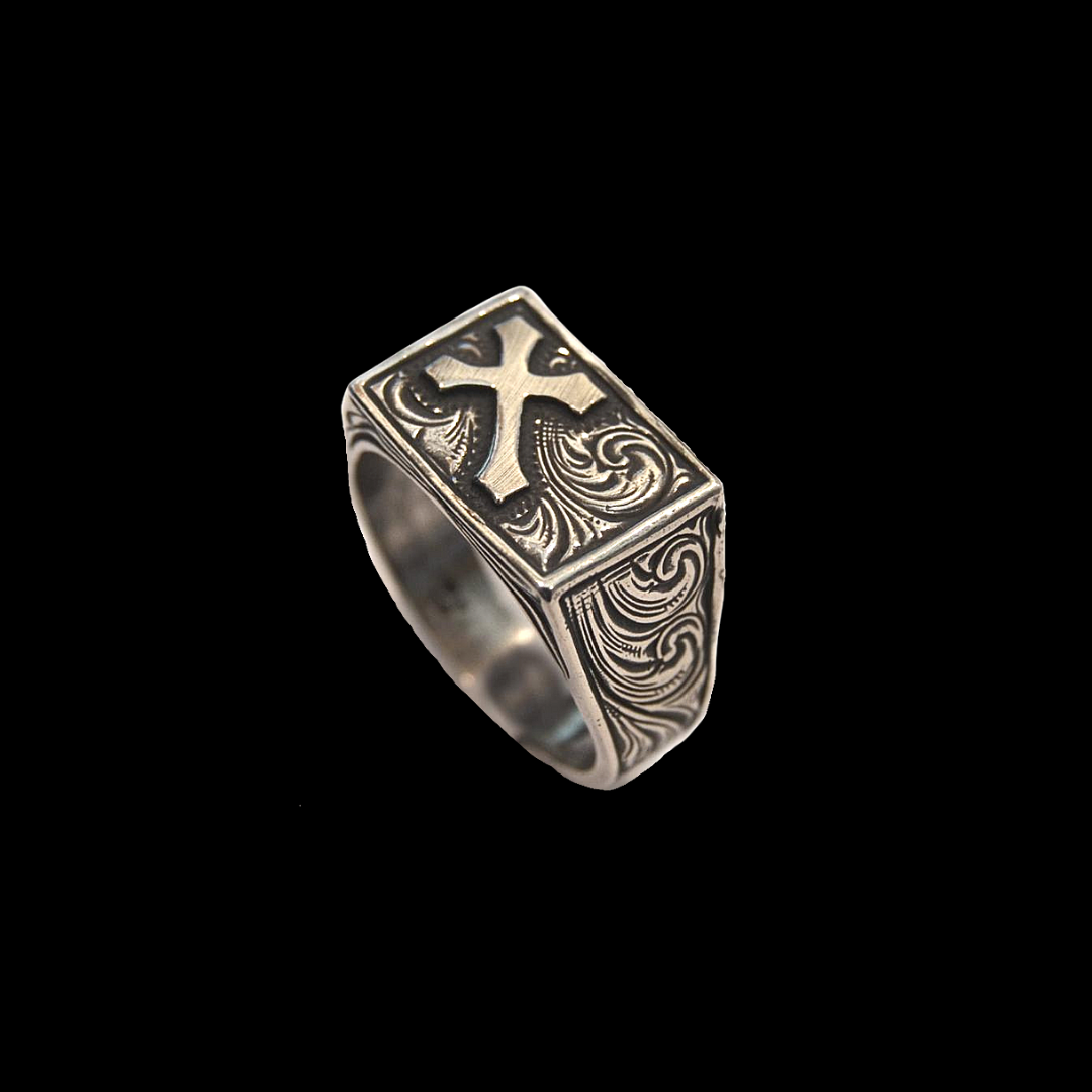 "Survivor" is a handmade solid sterling ring that features an overlaid cross and western style hand engraved scrolling on the top of the ring as well as on either side of it tapered band.