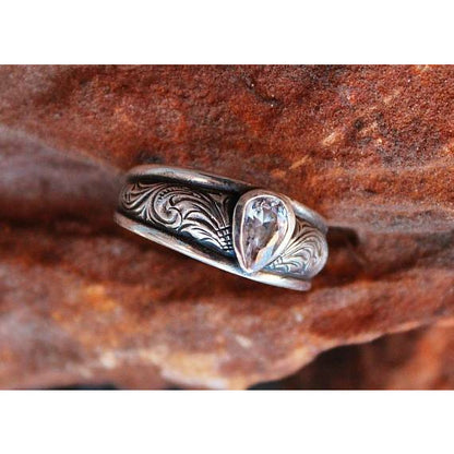"Mya" is a custom sterling silver ring that features an 8mm x 5mm pear shaped bezel set cubic zirconia with an elegant western style hand engraved scrolling around the tapered band.